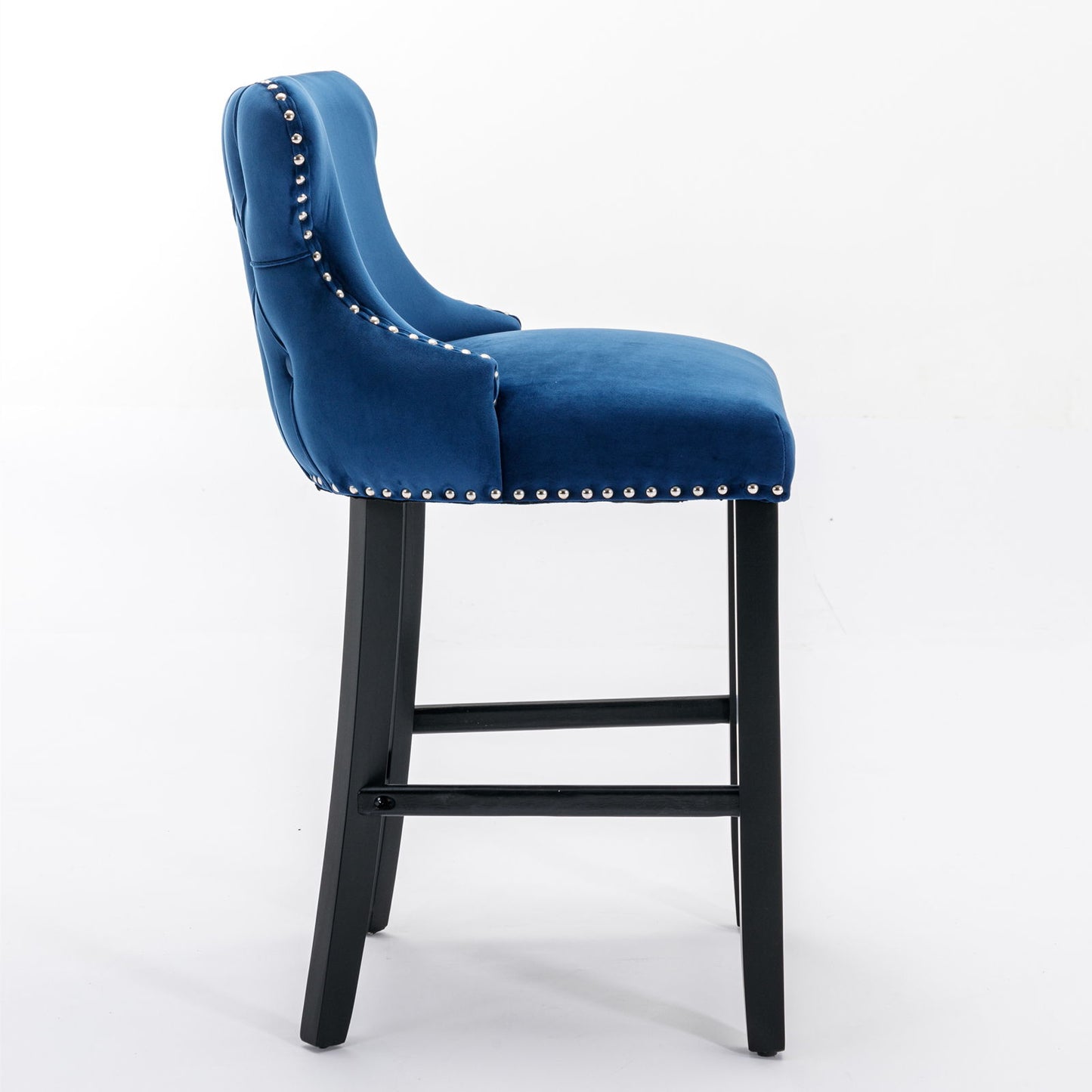 Side view of a Contemporary Velvet Upholstered Wing-Back Barstool featuring button tufted decoration, chrome nailhead trim, and wooden legs with footrests; leisure style bar chair in blue velvet (Set of 2).