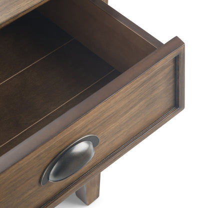 A close-up of the Acadian - Bedside Table, Handcrafted, features an open wooden drawer with a dark metal cup pull handle, revealing the drawer’s interior and part of the table’s frame against a white background.