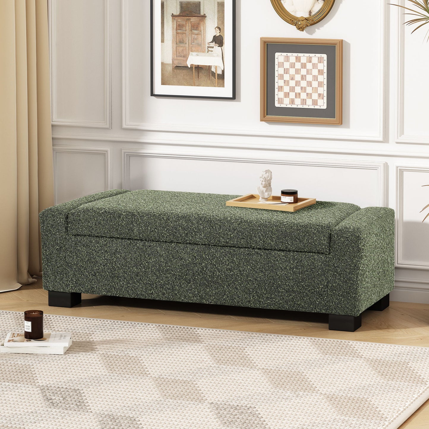 A Textured Fabric Ottoman Bench With Hinged Lid in green sits against a white wall with framed art and beige curtains in a bright living room. On top of the bench are a tray, book, and candle.