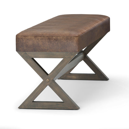 The Salinger - Large Upholstered Ottoman Bench features a padded, textured leather seat and sturdy wooden legs in an X-shape, shown against a plain white background.