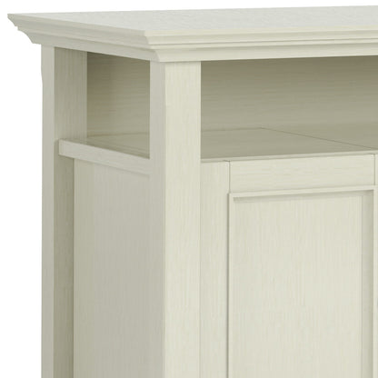 A close-up of the Amherst TV Media Stand, Handcrafted, featuring a light wood finish, open top shelf, closed panel door below, simple clean lines, and a slightly textured surface.