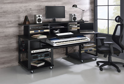 The Megara Music Desk features multiple storage options, a spacious workspace for keyboard, monitor, speakers, and audio gear, plus room for an office chair—all beside a tall window and set against a wood-paneled wall.