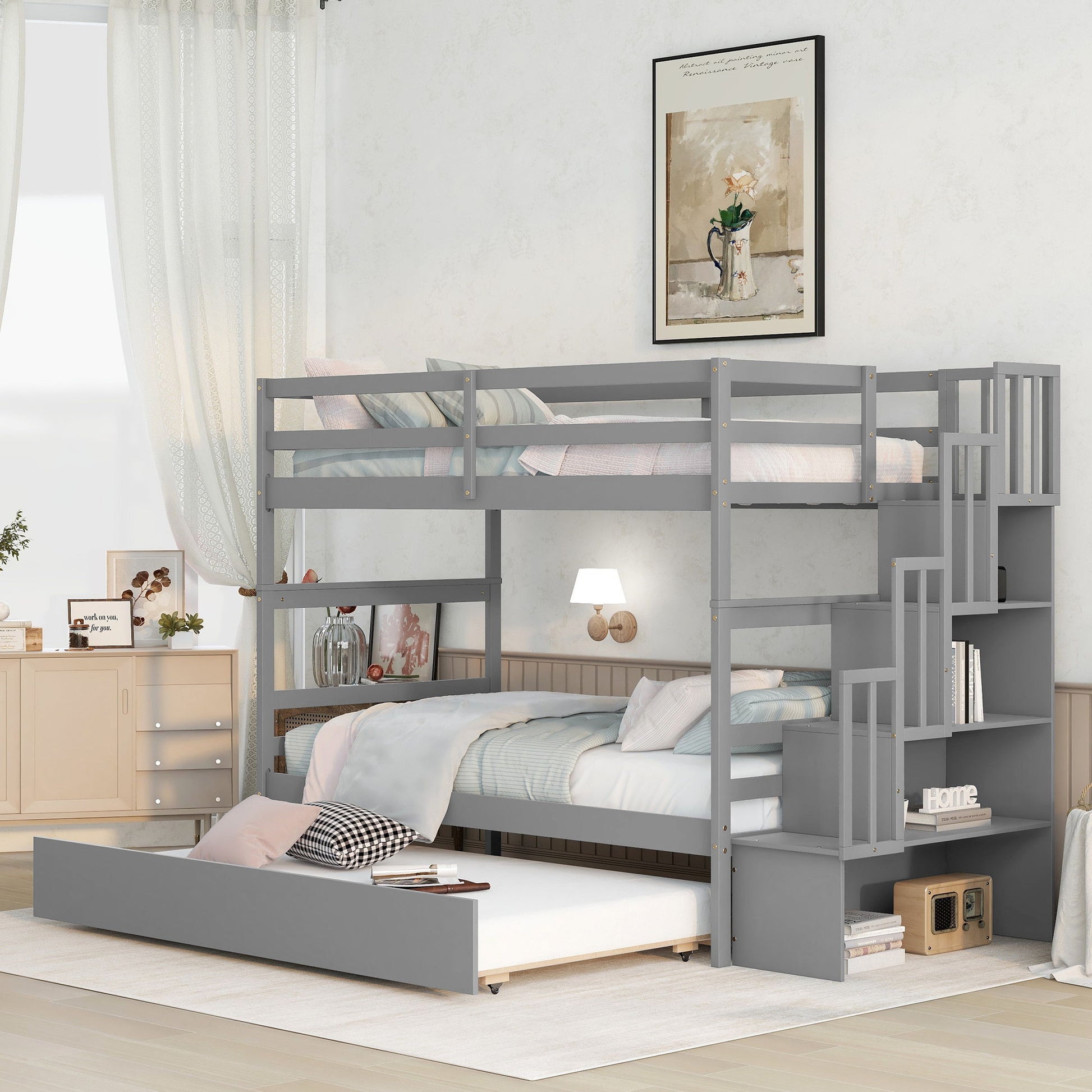 A modern bedroom featuring the Twin Over Twin Bunk Beds With Twin Trundle And Stairway Storage Function in gray, with built-in shelf stairs and a pull-out trundle. Decor includes soft colors, light curtains, cabinets, and a framed picture.