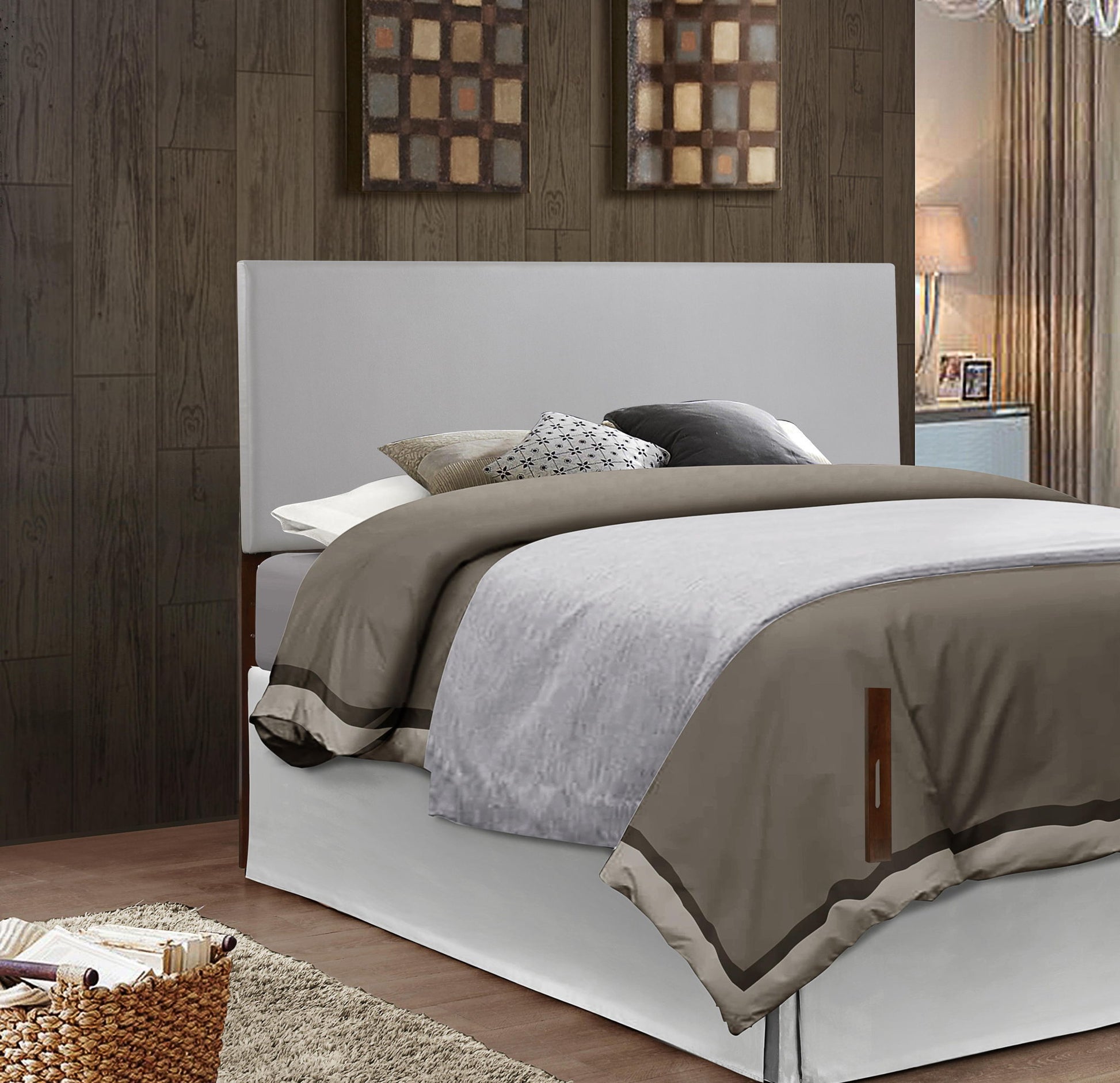 A cozy bed with gray and beige bedding, multiple pillows, and the Nova - Headboard stands against a dark wood-paneled wall with two framed artworks above. Nearby are a lamp and a wicker basket.