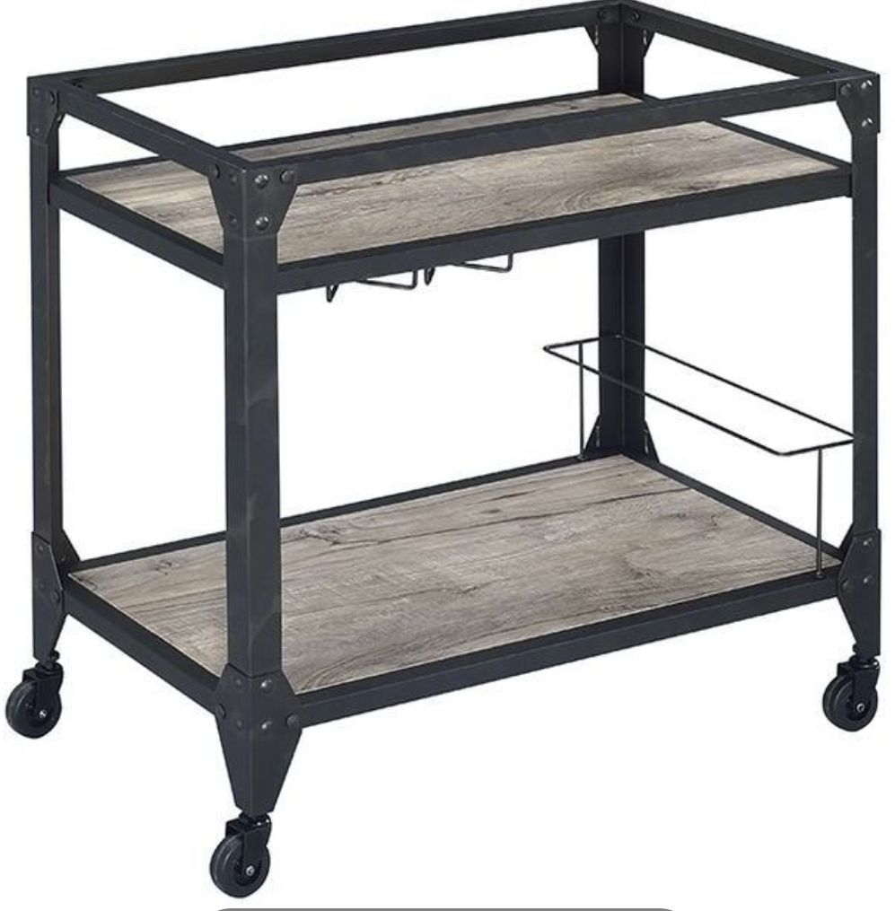 The Jorgensen Serving Cart in Rustic Oak/Charcoal features two wood-finish shelves, a black metal frame, wine glass rack, side bottle holder, and four rolling caster wheels.