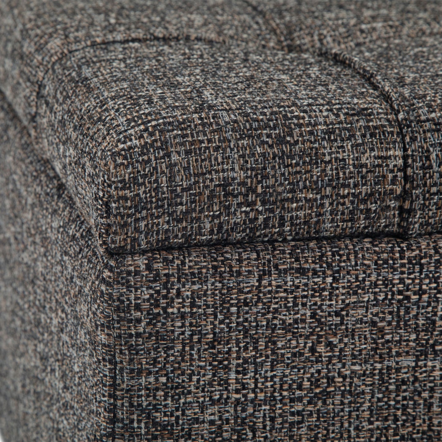 Close-up of the Harrison Upholstered Coffee Table Storage Ottoman, highlighting its tightly woven, textured gray, brown, and black fabric with visible seams and stitching.
