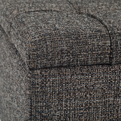 Close-up of the Harrison Upholstered Coffee Table Storage Ottoman, highlighting its tightly woven, textured gray, brown, and black fabric with visible seams and stitching.