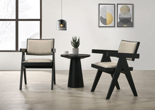 Modern living room featuring the Jasper 3 Piece Arm Chairs and Console Table set in Ebony Black, paired with beige cushions, a potted succulent, coffee cup, pendant light, abstract wall art, and a snowy scene outside a large window.