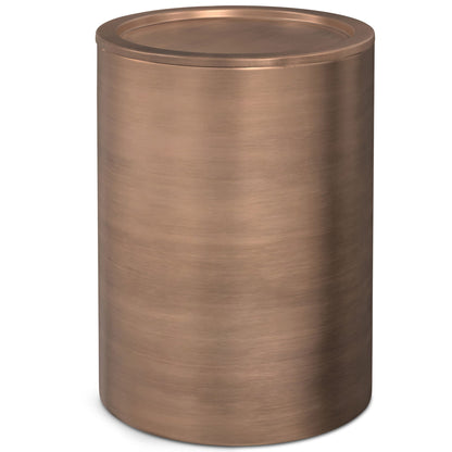The Corbin Handcrafted Metal Side Table features a cylindrical shape with a metallic, brushed copper finish and a flat, round lid.