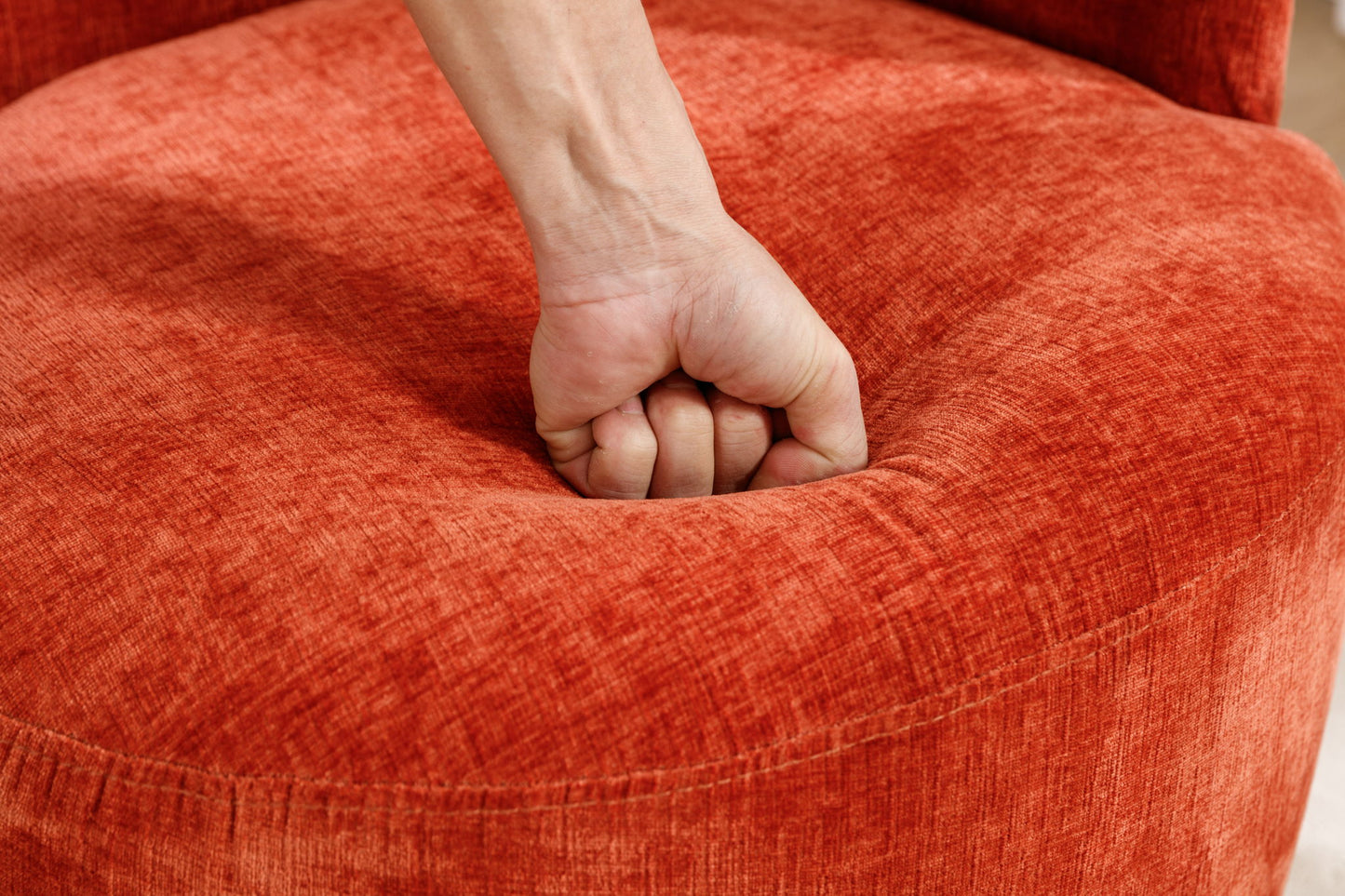 A hand clenched in a fist presses down on the seat of the Chenille Fabric Swivel Accent Armchair Barrel Chair With Powder Coating Metal Ring, creating an indentation in its soft, textured upholstery.