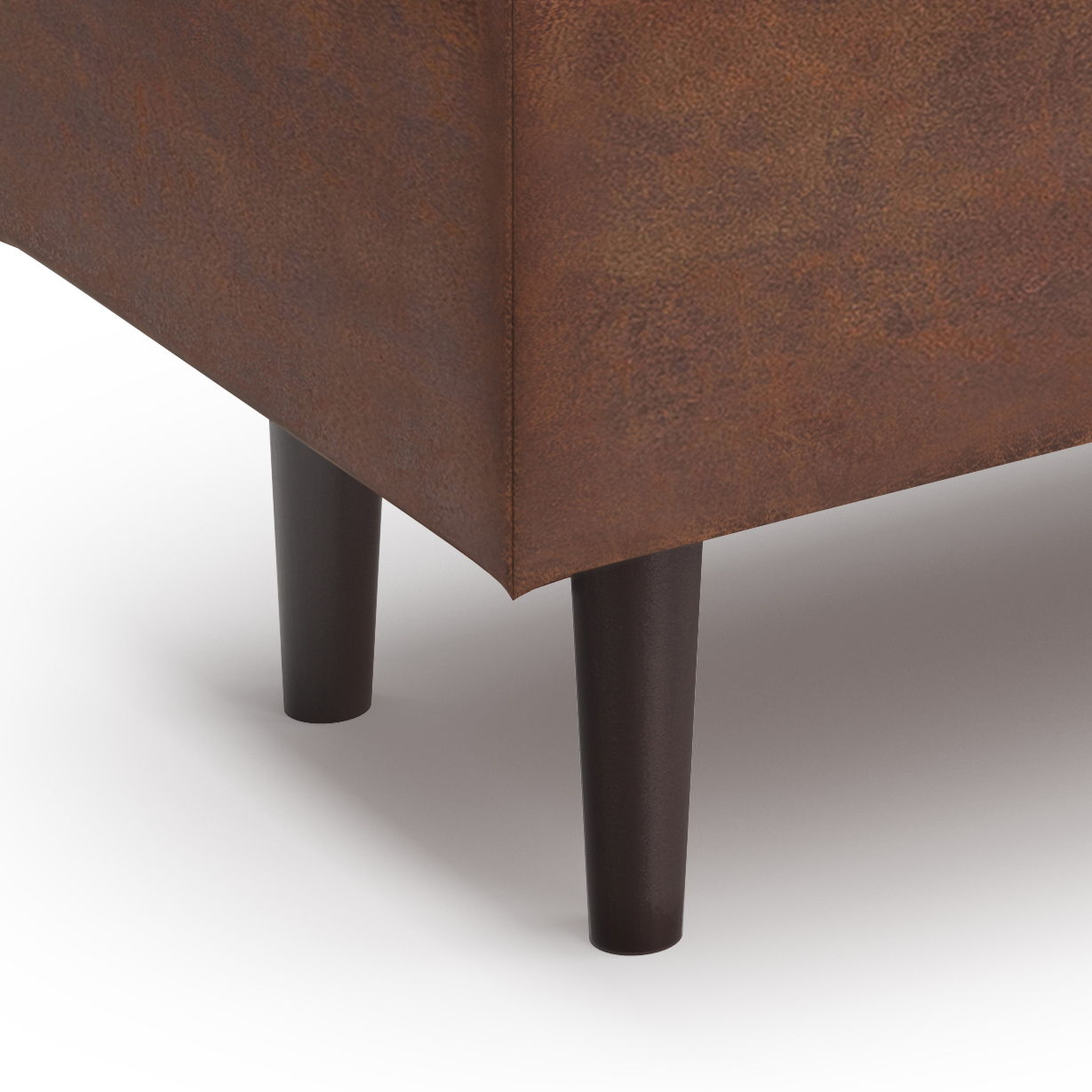 Close-up of the corner of the Shay Large Square Coffee Table Storage Ottoman in brown textured fabric, highlighting two dark wooden legs against a white background.