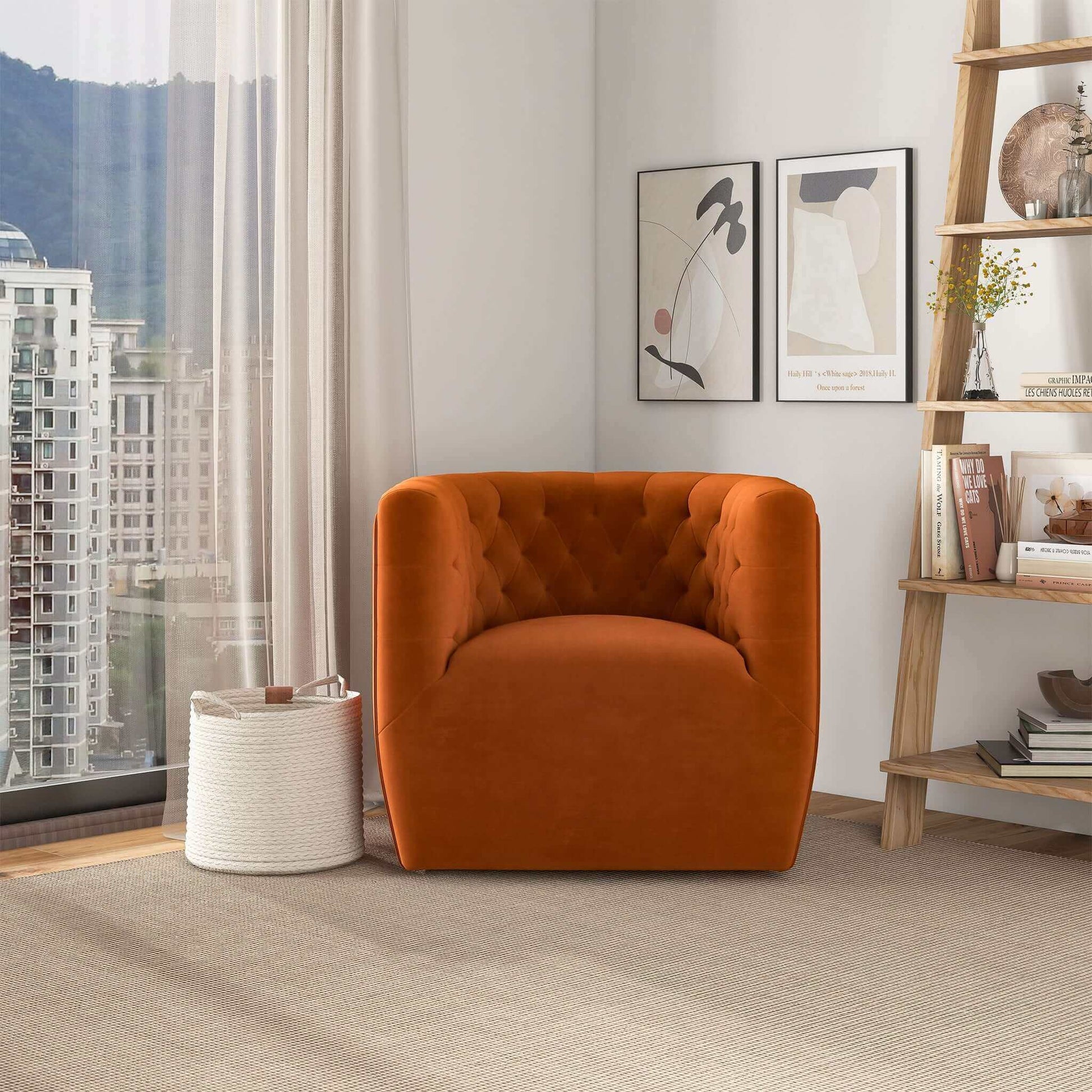 A modern living space featuring the Delaney Ergonomic Design Swivel Chair in orange velvet, a white woven basket, two abstract art prints, a wooden shelf with books and decor, and large windows overlooking city buildings.