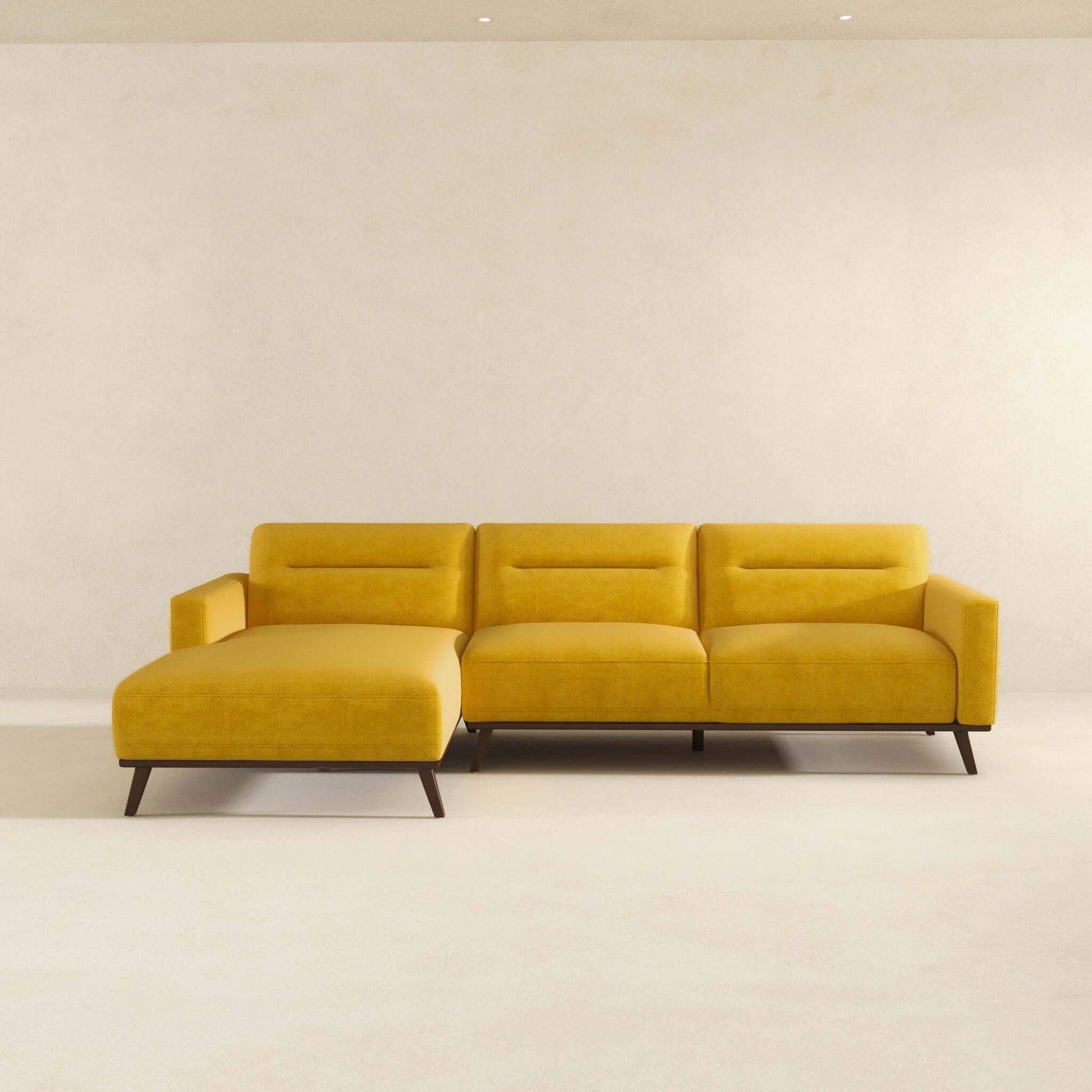 The Ella L-Shaped Sectional Couch in yellow features a left-side chaise lounge and sits against a plain, light wall in a minimalistic room with a light floor.