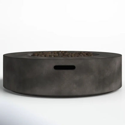 The Fiber Reinforced Outdoor Fire Pit Table in black/gray is a modern round fire pit made of smooth concrete, featuring a central area with small rocks and a rectangular cutout on the side.