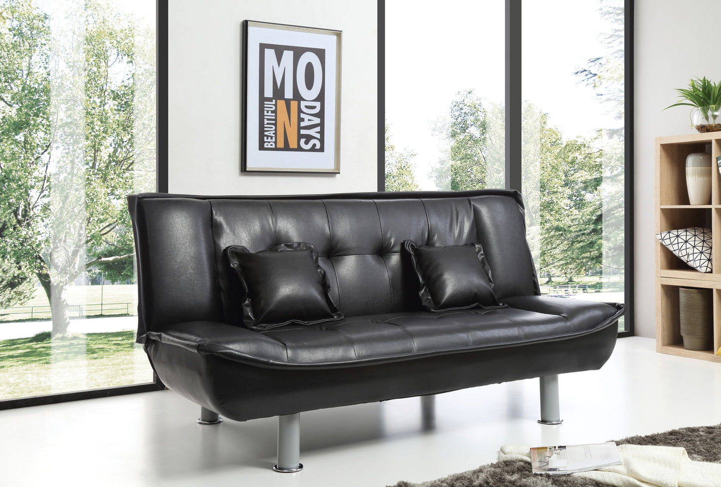 A modern room with large windows showcases the Lionel - Sofa Bed in black leather with two matching pillows. Framed wall art hangs behind, a decorated bookshelf sits right, and sunlight brightens the stylish space.