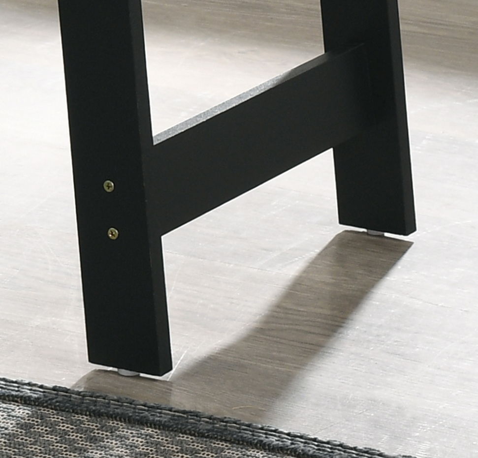 Close-up of the black wooden legs of the Kenzo End Table with Faux Marble Top Finish, standing on a light-colored floor with part of a textured rug visible in the bottom left corner.