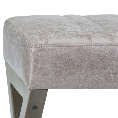 Close-up of the Salinger - Large Upholstered Ottoman Bench, showcasing its soft light gray velvet cushion and angular wooden leg. Fabric texture and detailed stitching are clearly visible.