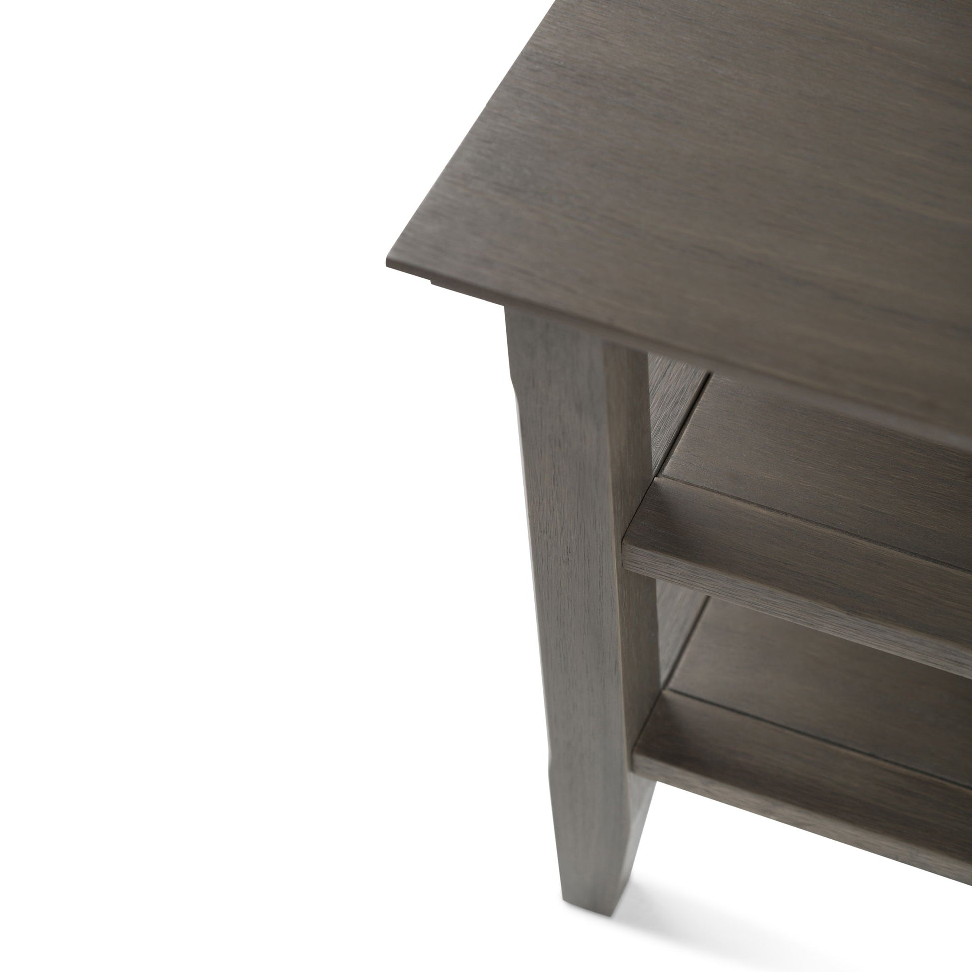 Close-up of the Acadian - Handcrafted End Table corner, highlighting its grayish finish, tabletop, supporting leg, and two lower shelves.