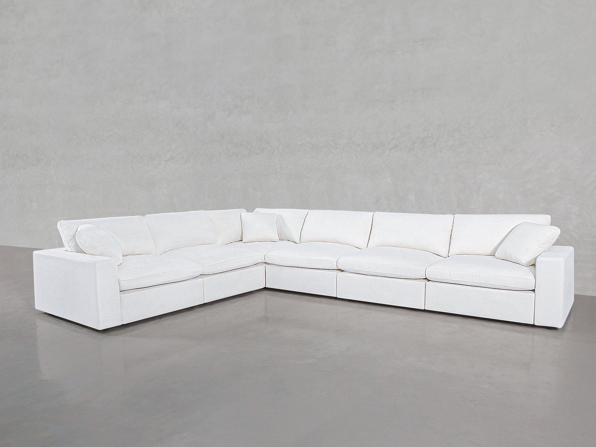 A spacious 6-Seat Modular Corner Sectional with clean lines and plush cushions is arranged in an L-shape against a light gray wall and floor.