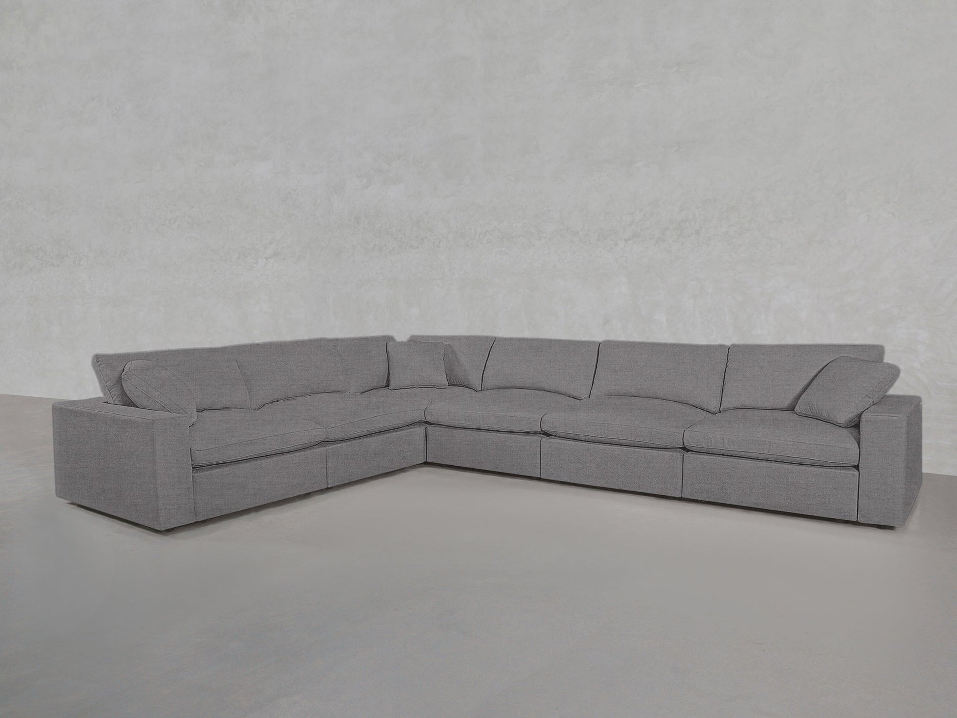 The 6-Seat Modular Corner Sectional features plush cushions and armrests in a modern gray L-shaped design, set against a light gray textured wall and smooth floor.