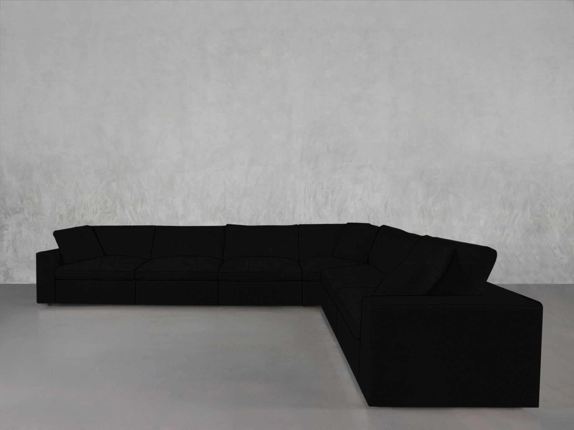 A 6-Seat Modular Corner Sectional in modern black with clean lines sits against a light gray textured wall on a smooth, light-colored floor.