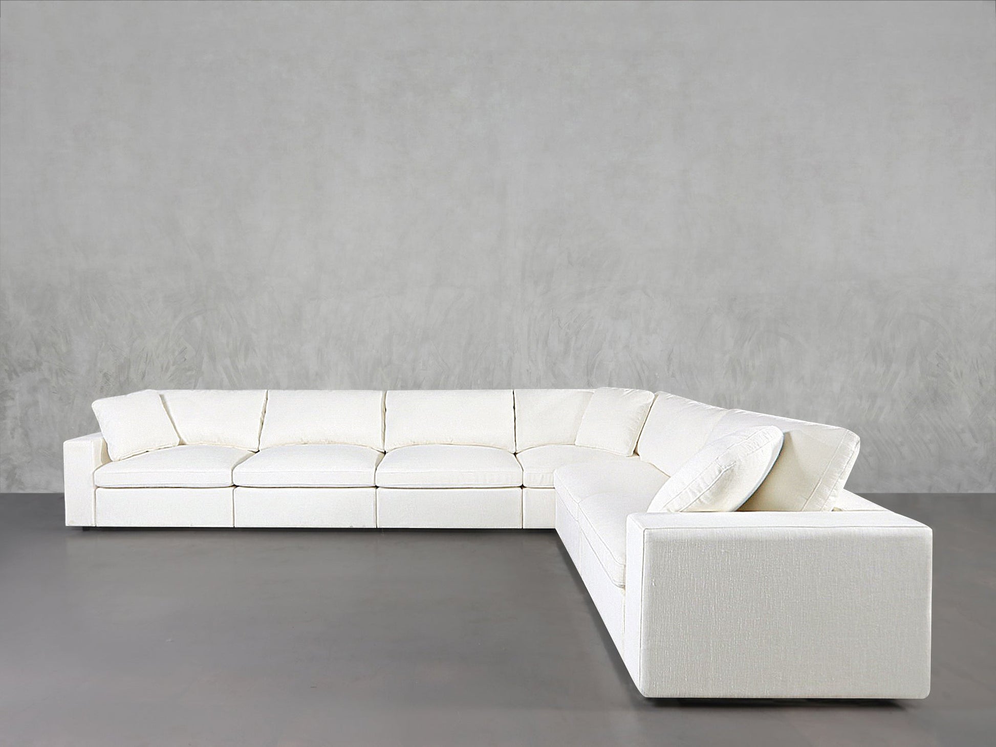 A 6-Seat Modular Corner Sectional in modern white with clean lines and plush cushions is set against a light gray wall on a gray floor.