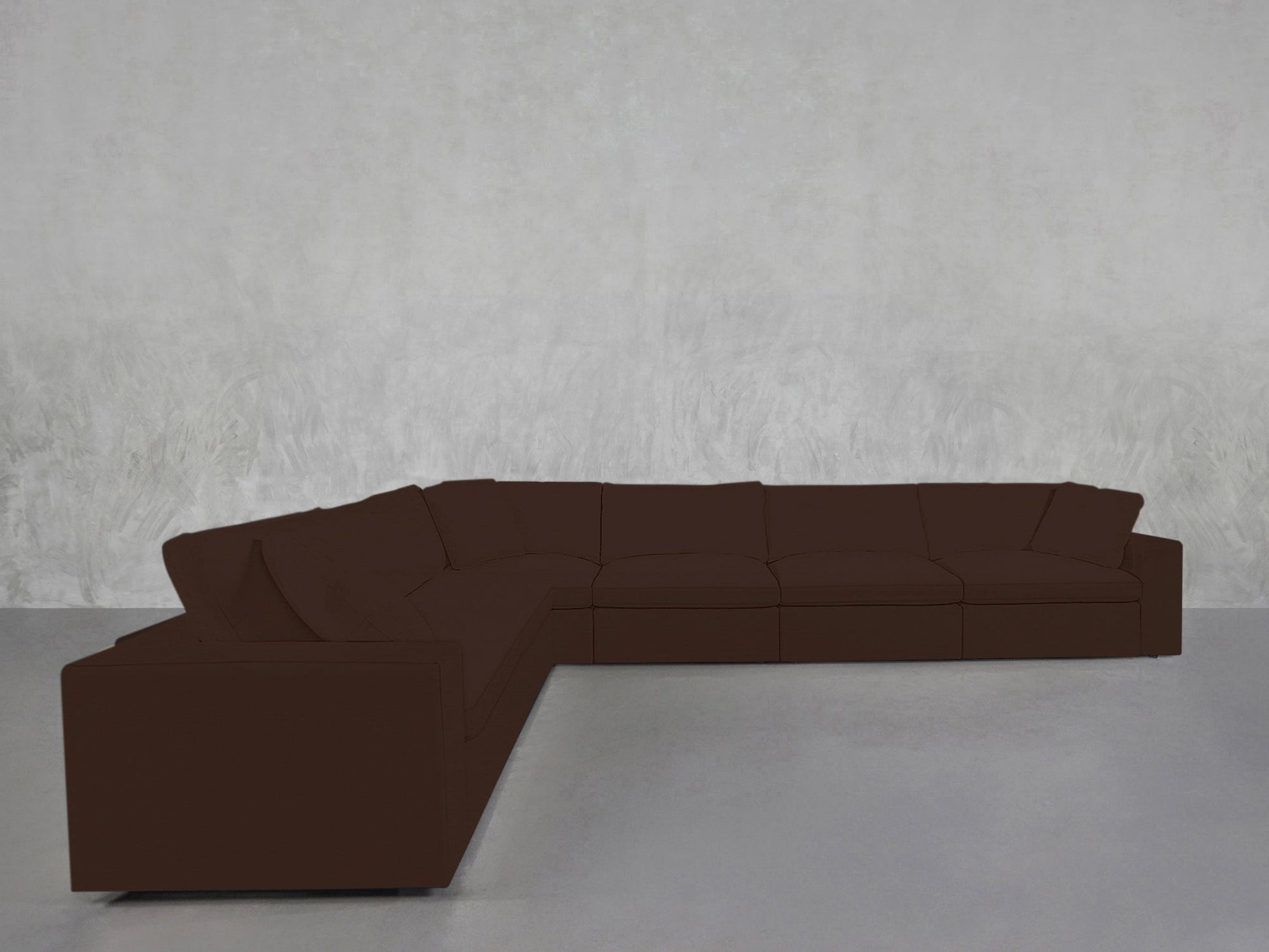 A 6-Seat Modular Corner Sectional in dark brown is placed against a light gray textured wall on a gray floor in a minimal, empty room.