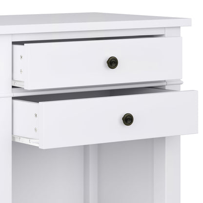 A close-up of the Carlton - Bedside Table, Handcrafted, shows its white finish and two partially open drawers with round, dark metal knobs. The bedside table boasts a simple, modern design with clean lines.