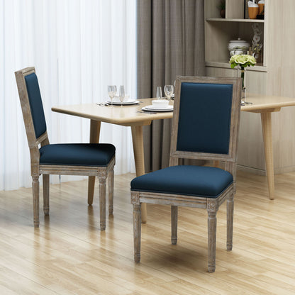 Two Traditional Style Dining Chairs With Fabric Upholstery, in dark blue, are placed near a light wood dining table set for a meal in a modern dining room featuring curtains and light wood flooring.