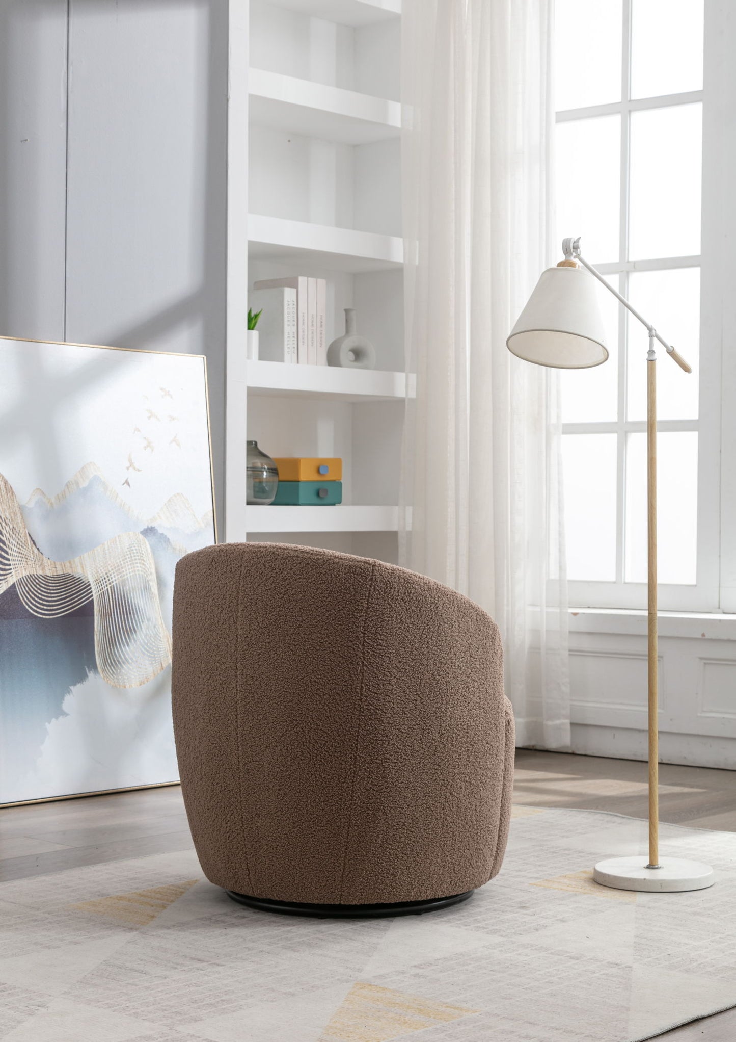 The Teddy Fabric Swivel Accent Armchair Barrel Chair with a powder coating metal ring sits in a bright room with a floor lamp, large window, white shelves, and abstract art as sunlight filters through sheer curtains.