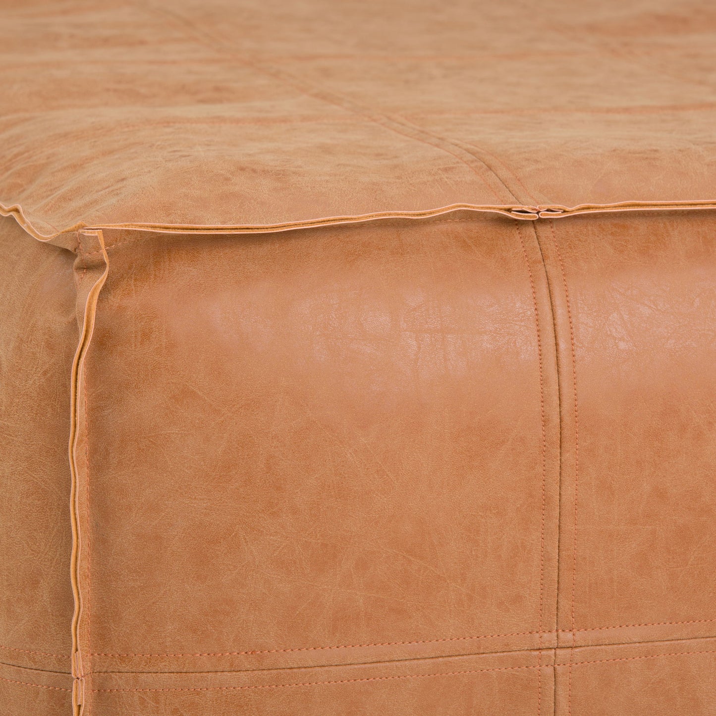 Close-up of the Brody Large Square Coffee Table Pouf in tan leather, featuring visible stitching and piping along the seams to highlight the texture and detailed craftsmanship.