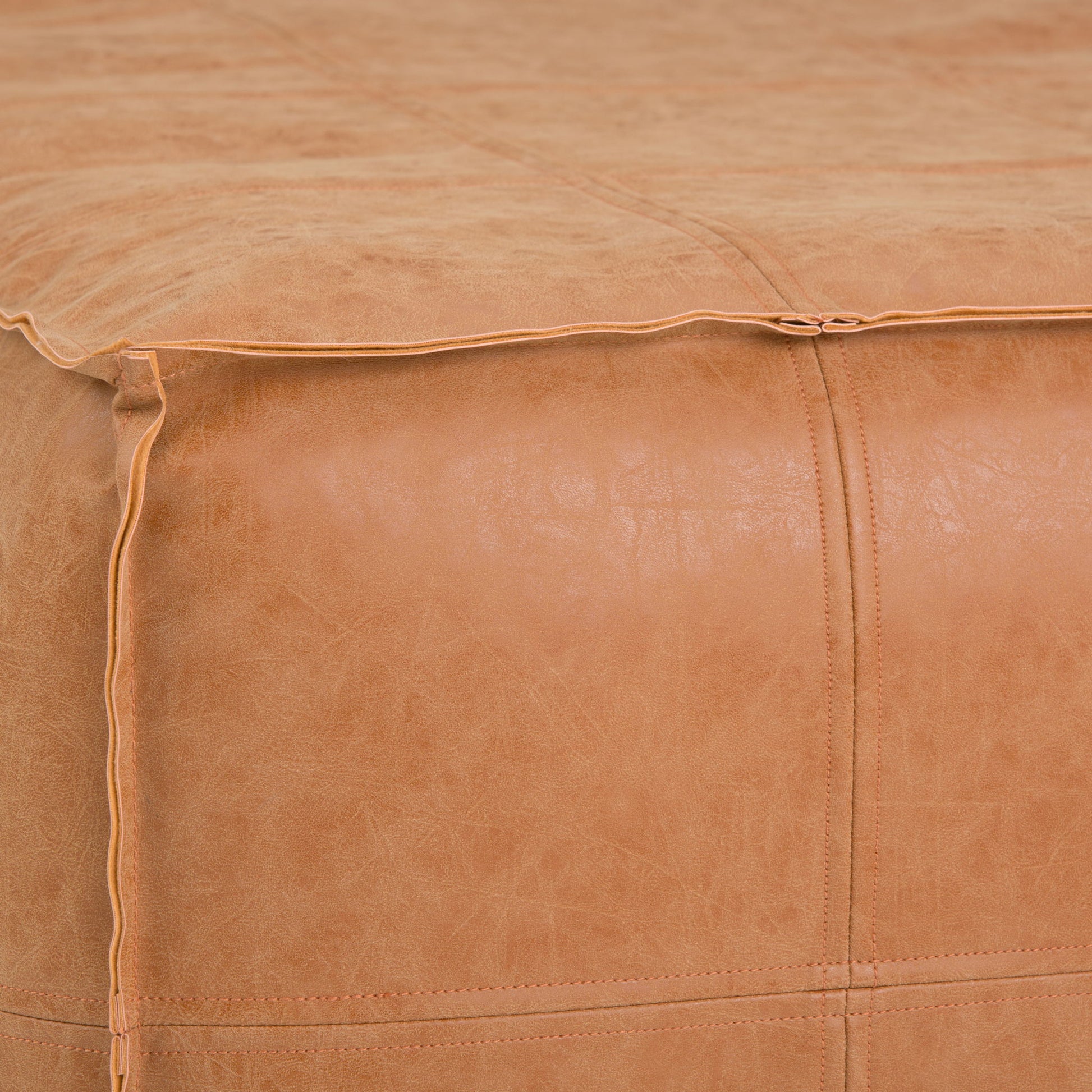 Close-up of the Brody Large Square Coffee Table Pouf in tan leather, featuring visible stitching and piping along the seams to highlight the texture and detailed craftsmanship.
