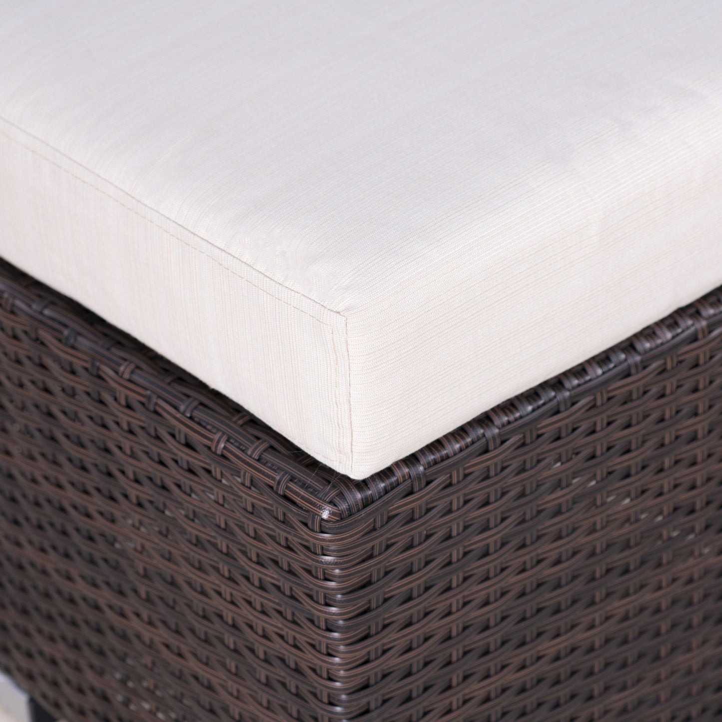 Close-up of the Santa Rosa - Outdoor Lounge Ottoman featuring a dark brown wicker base and a thick, light beige cushion. The woven texture and fabric details are clearly visible.