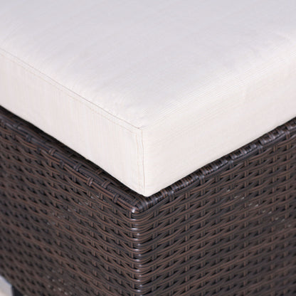 Close-up of the Santa Rosa - Outdoor Lounge Ottoman featuring a dark brown wicker base and a thick, light beige cushion. The woven texture and fabric details are clearly visible.
