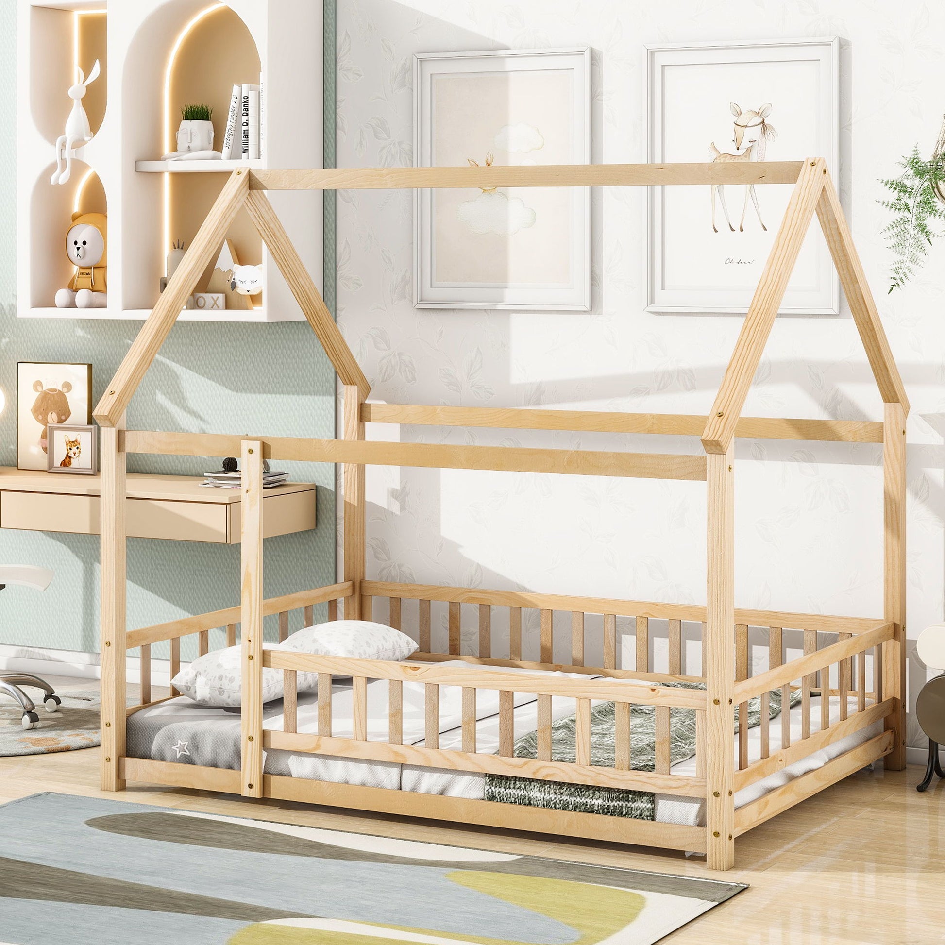 The Floor Wooden Bed With House Roof Frame and Fence Guardrails sits in a cozy, modern kids' room with neutral tones, soft decor, shelves of toys, and a low mattress topped with pillows and a blanket.