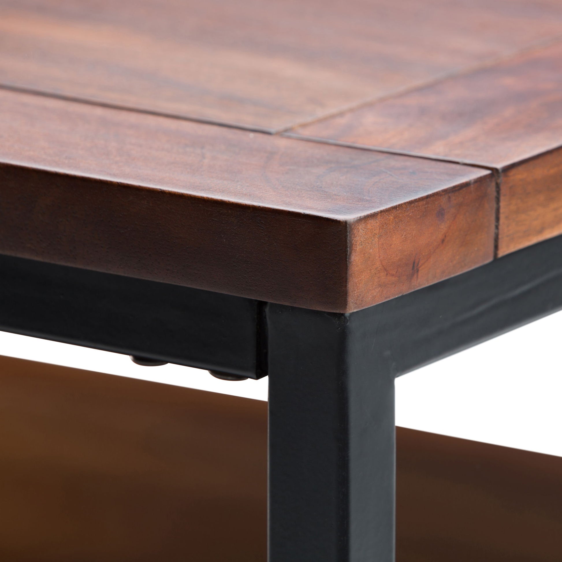 Close-up of the Skyler - Handcrafted Table’s corner, featuring smooth wood grain and a sturdy dark metal frame, highlighted against a white background.