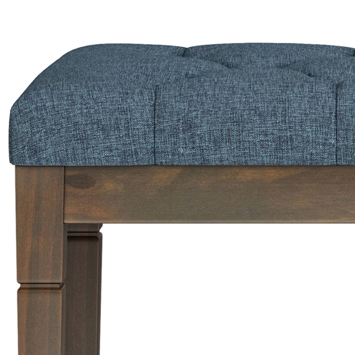 Close-up of the Waverly - Upholstered Tufted Ottoman Bench, showing its dark wooden frame and padded, tufted blue-gray fabric seat with only the seat and upper legs visible.