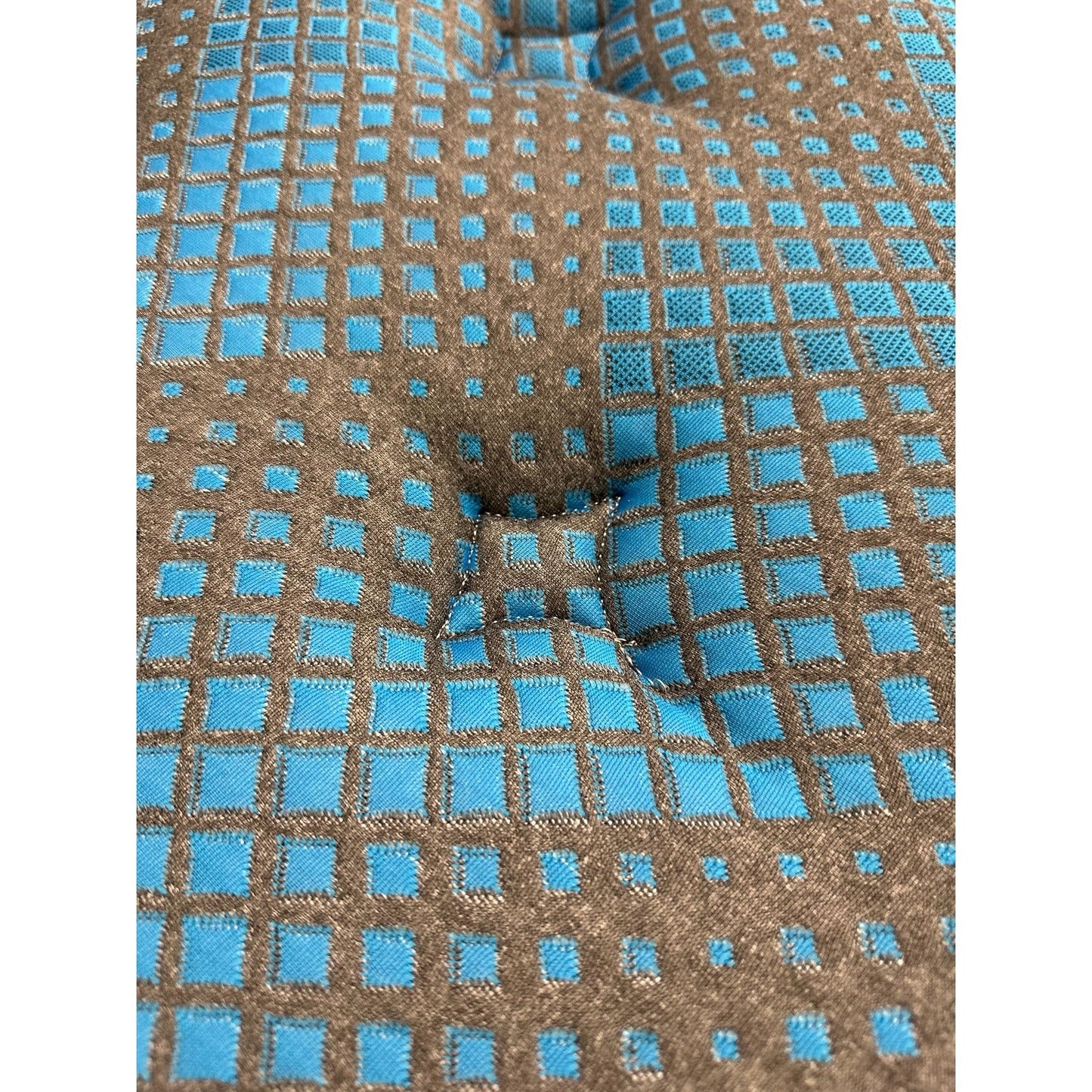 Close-up of the Comfort Care - 9" 2 Sided Foam Core Mattress, Medium Comfort, showcasing textured fabric with a brown and blue square pattern and button-tufted center indentation. The grid design highlights blue squares outlined in brown.