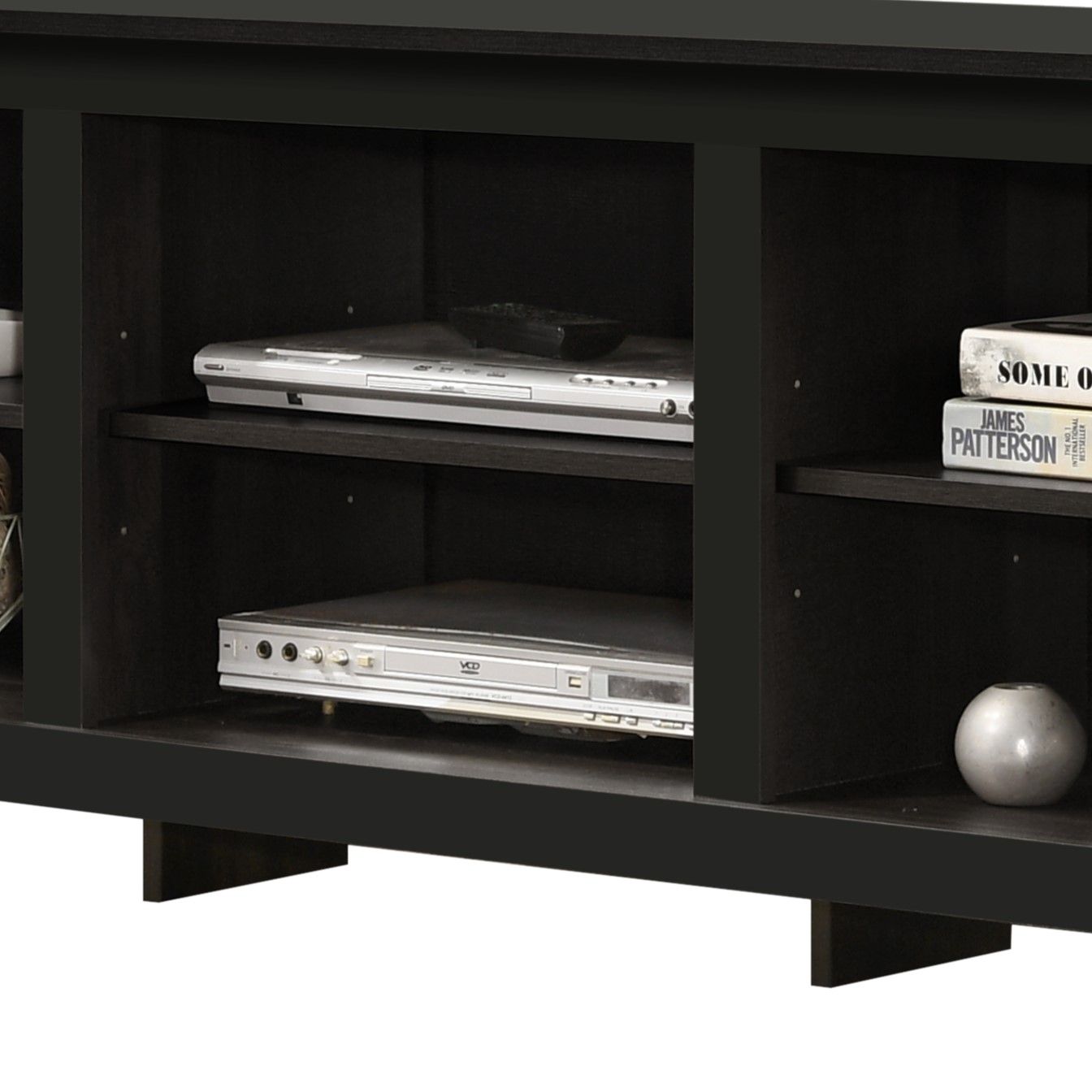 The Benito TV Stand features open shelves for a DVD player, VCR, books, a dish, décor accents like a round vase, and built-in cable management in a dark wood finish.