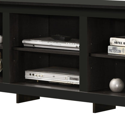 The Benito TV Stand features open shelves for a DVD player, VCR, books, a dish, décor accents like a round vase, and built-in cable management in a dark wood finish.