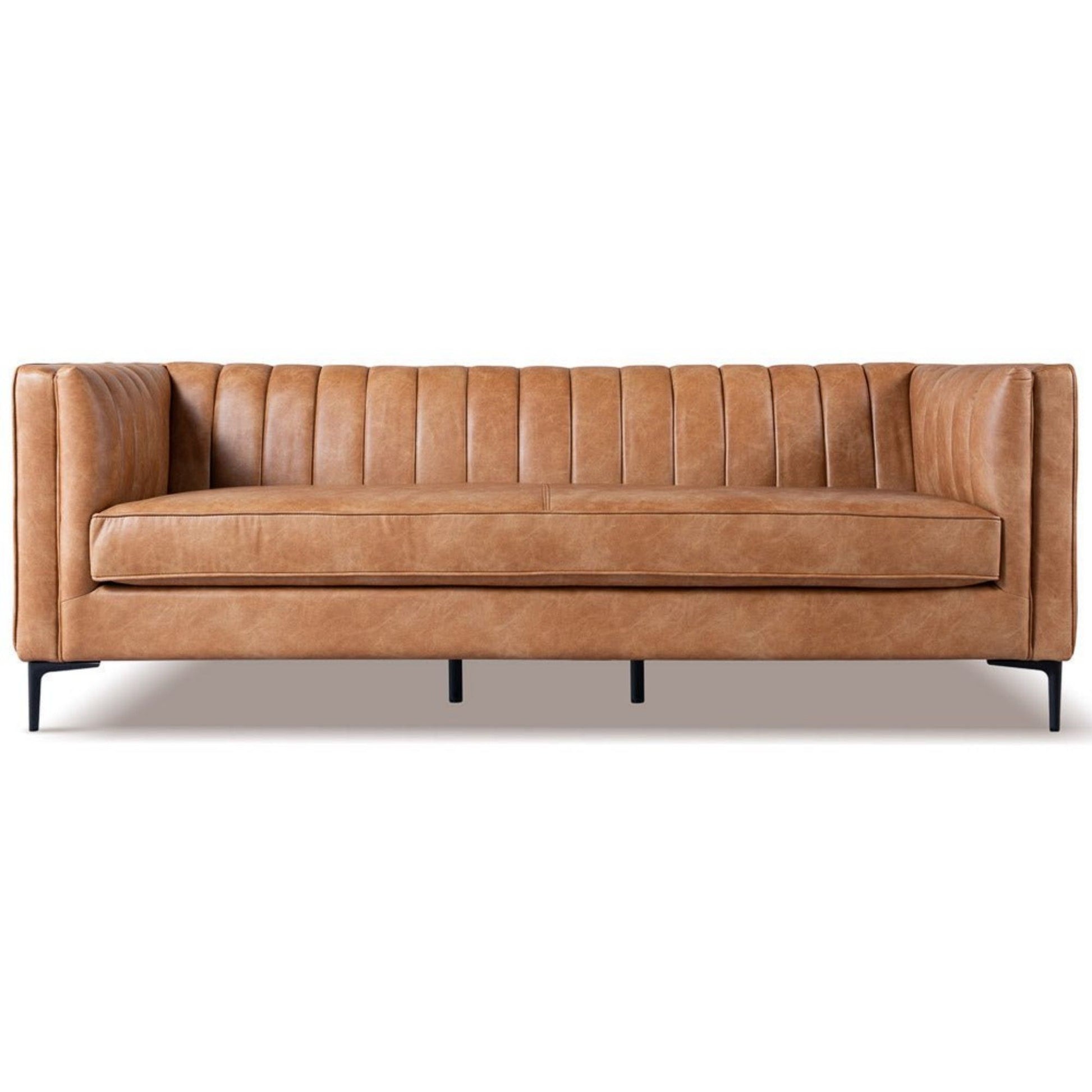 The Angelina - Channel Tufted Sofa features modern tan leather upholstery, vertical tufting on the back and sides, straight arms, and slender black metal legs, shown from the front against a white background.