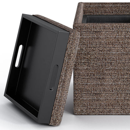 A close-up of the Rockwood Upholstered Cube Storage Ottoman With Tray shows its brown textured fabric, removable lid with handle cutouts propped nearby, and visible spacious interior.