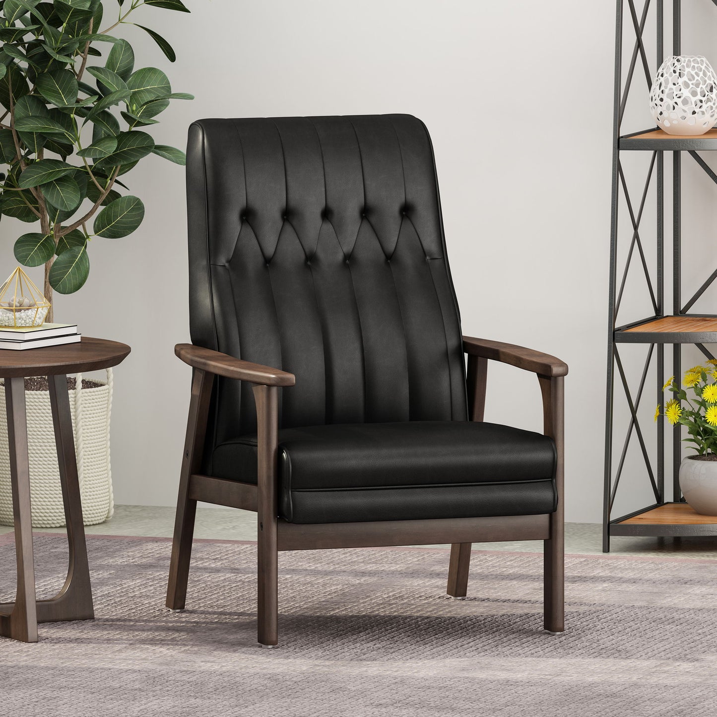 The Mid Century Modern Upholstered Accent Chair, featuring black tufted leather and wooden armrests and legs, sits on a light gray rug with a round side table, leafy potted plant, and metal shelf with flowers in the background.