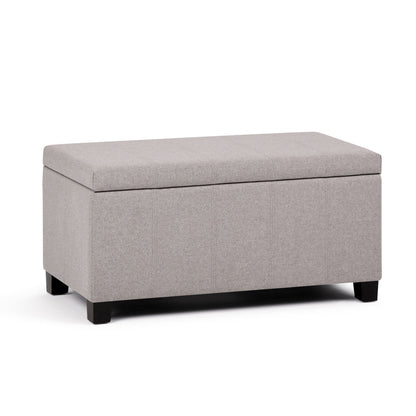 The Dover Upholstered Storage Ottoman Bench features a rectangular design in light gray fabric, a flip-top lid, and short black wooden legs, displayed against a white background.