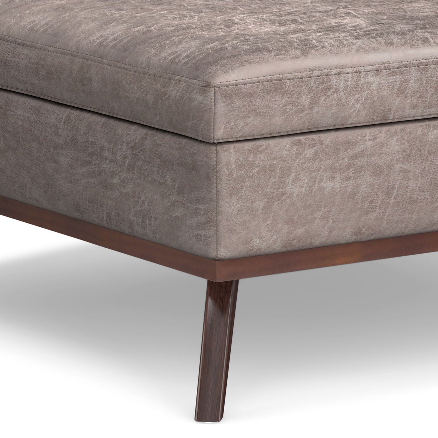 Close-up of the corner of the Owen - Multifunctional Square Coffee Table Storage Ottoman with taupe textured upholstery and dark wooden legs, shown on a white background.