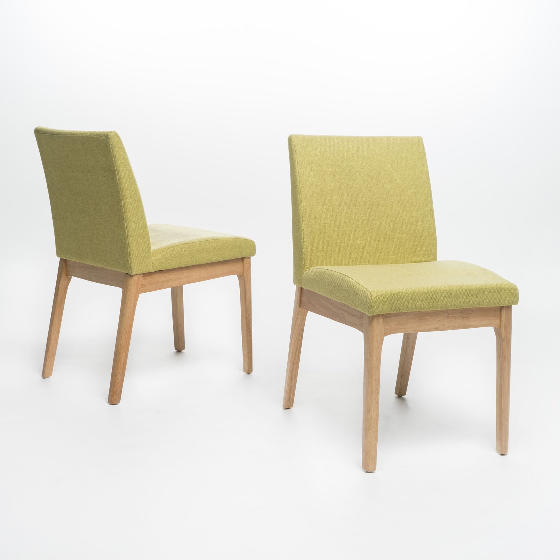 The Contemporary Fabric Comfort Dining Chairs (Set of 2) feature modern armless designs with light wood legs and light green upholstered seats and backs. One chair faces forward, while the other is angled left on a white background.