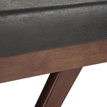 Close-up of the Chanelle Mid-Century Ottoman Bench reveals a dark gray cushioned seat and angled wooden legs, highlighting the bench’s materials and textures.