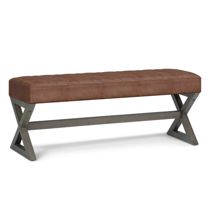 The Salinger - Large Upholstered Ottoman Bench features a tufted brown leather cushion atop dark wooden X-crossed legs, joined by a horizontal support bar.