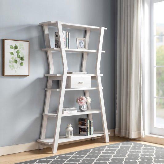 The Modern Home Display Cabinet 4 Tier Open Shelving With Center Drawer - White Oak stands in a corner by a window with long curtains, showcasing books, decor, a potted plant, and a small drawer. A framed leaf print hangs above.