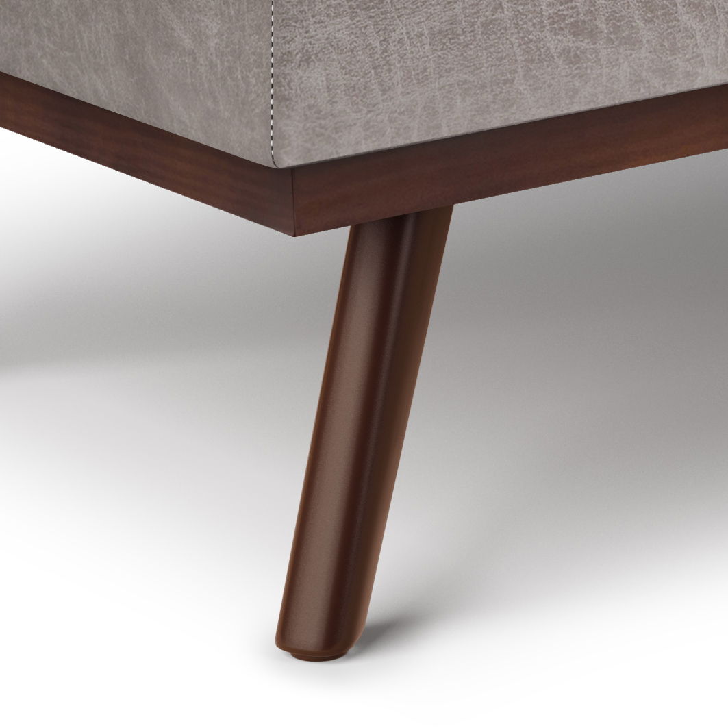Close-up of a dark wood leg on the Owen Lift Top Large Coffee Table Storage Ottoman, featuring light gray upholstered fabric with visible stitching and mid-century style design.